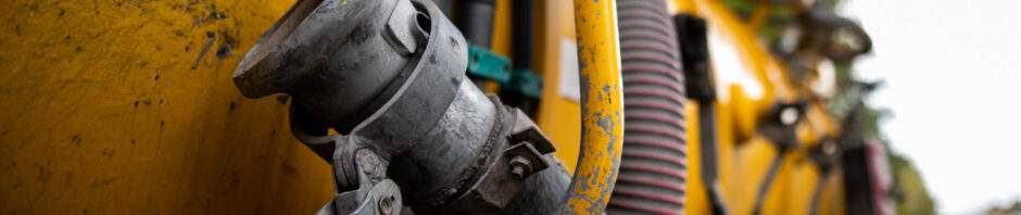 Side view of powerful professional modern yellow sewage sewerage truck working near a house pumping basement canalisation water.
