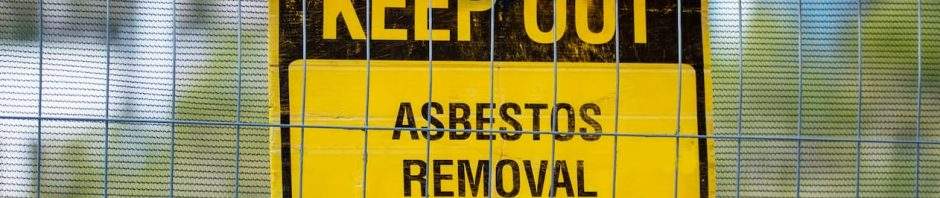 KEEP OUT ASBESTOS REMOVAL warning sign on a construction fence. This image represents our specialized hazardous waste management, asbestos abatement, and environmental remediation services, ensuring safe and compliant removal of dangerous materials.